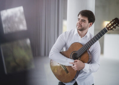 Rostyslav Holubov, Ukrainian classical guitarist, holding his guitar during a professional photo session.